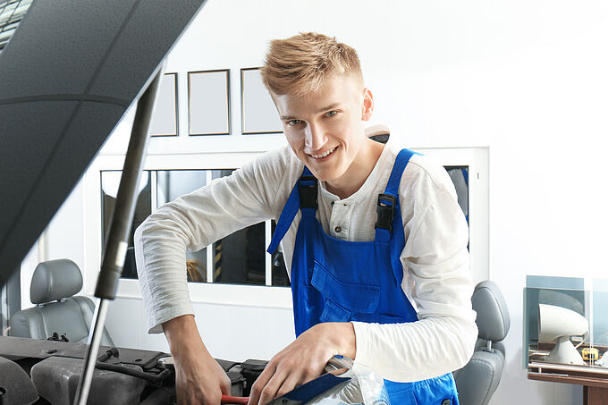 Young mechanic repairing car in body shop